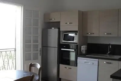 a kitchen with a refrigerator and a microwave and a table at Appartement 8 pers. - Domaine de Padulone ALERIA in Aléria