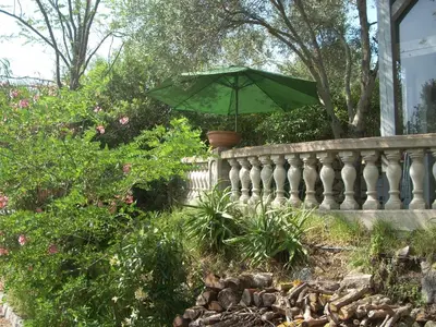 a green umbrella in a pot on a fence at CHAMBRE INDEPENDANTE climatisée, cuisine d'été, piscine in Sartène
