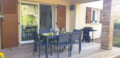 a dining table and chairs on a patio with a glass door at Appartement Lena 6 pers piscine 500 m plage in Sainte-Lucie de Porto-Vecchio