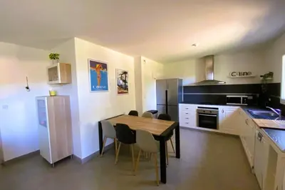 a kitchen with a wooden table and a dining room at Appartement Lena 6 pers piscine 500 m plage in Sainte-Lucie de Porto-Vecchio