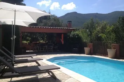 a swimming pool with two chairs and an umbrella at Casa de Patarra gîte dans le maquis avec piscine privée in Peri