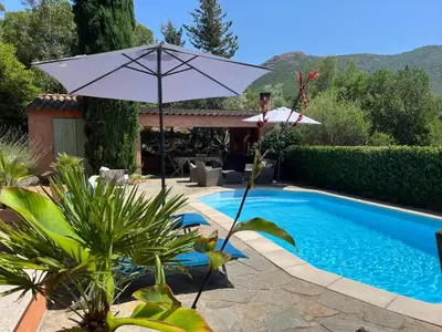 a white umbrella next to a swimming pool at Casa de Patarra gîte dans le maquis avec piscine privée in Peri