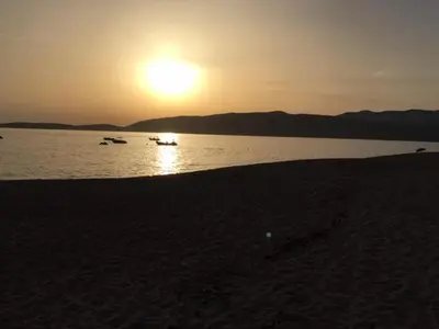 a sunset on a beach with boats in the water at La rose bleue (2) in Olmeto
