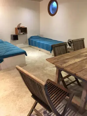 a room with two beds and a table and chairs at La rose bleue (2) in Olmeto