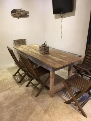 a wooden table with two chairs and a television at La rose bleue (2) in Olmeto