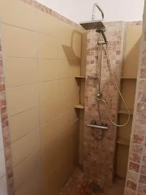 a shower in a bathroom with a brick wall at OVU Piscine chauffée Entre mer et montagne à 1 km de la mer in Solaro