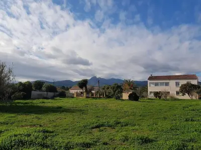 a green field with a house and mountains in the background at OVU Piscine chauffée Entre mer et montagne à 1 km de la mer in Solaro