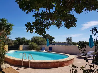 a pool with chairs and umbrellas in a yard at OVU Piscine chauffée Entre mer et montagne à 1 km de la mer in Solaro