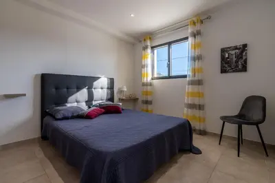 a bedroom with a large bed and a chair at Afa proche Ajaccio, magnifique villa avec piscine privée 8 personnes in Afa