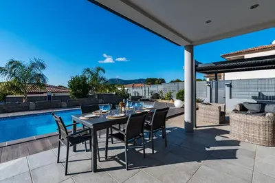 a patio with a table and chairs and a pool at Afa proche Ajaccio, magnifique villa avec piscine privée 8 personnes in Afa