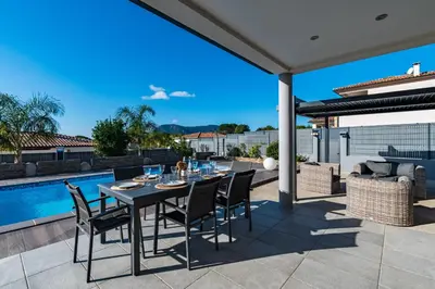 a patio with a table and chairs and a pool at Afa proche Ajaccio, magnifique villa avec piscine privée 8 personnes in Afa