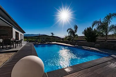 a swimming pool next to a house at Afa proche Ajaccio, magnifique villa avec piscine privée 8 personnes in Afa