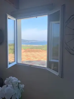 a room with two windows and a vase of flowers at Panorama exceptionnel sur les hauteurs de Propriano in Propriano
