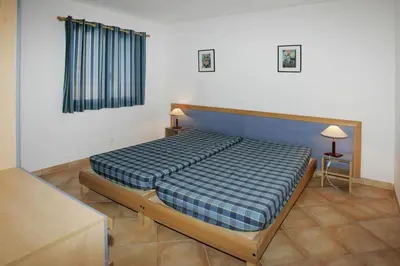 a bedroom with a bed with a blue plaid blanket at Apartment by Lido Beach & Biguglia Lagoon in Borgo