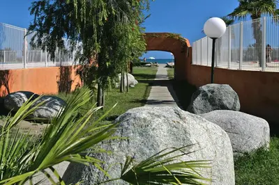 a garden with rocks and an arch over a walkway at Apartment by Lido Beach & Biguglia Lagoon in Borgo