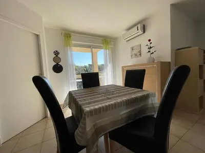 a dining room with a table and chairs and a window at Appartement tout confort 2-4 pers 500 m de la plage avec piscine et wifi in Santa-Maria-Poggio