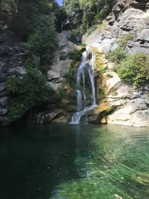a waterfall on a rocky hill with a body of water at Appartement tout confort 2-4 pers 500 m de la plage avec piscine et wifi in Santa-Maria-Poggio
