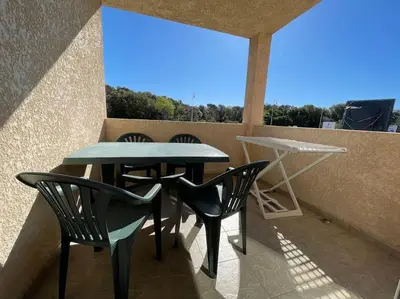 a patio with a table and chairs on a balcony at Appartement tout confort 2-4 pers 500 m de la plage avec piscine et wifi in Santa-Maria-Poggio