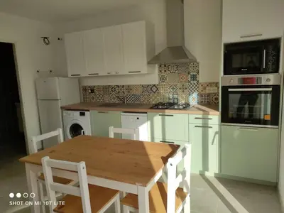 a kitchen with white cabinets and a wooden table at Grand studio classé 3 etoiles in Tavera
