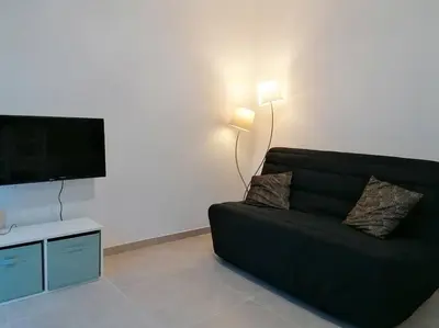 a living room with a black couch and a flat screen tv at Grand studio classé 3 etoiles in Tavera