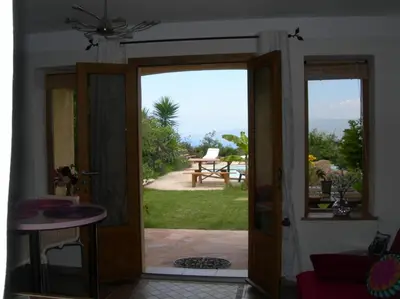 an open door to a patio with a view of a table at Petit coin de paradis, vue panoramique mer &montagne, piscine privée... in Calcatoggio
