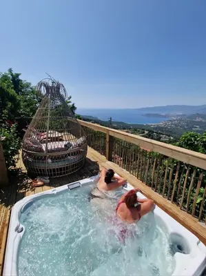 two people in a hot tub on a deck at Petit coin de paradis, vue panoramique mer &montagne, piscine privée... in Calcatoggio