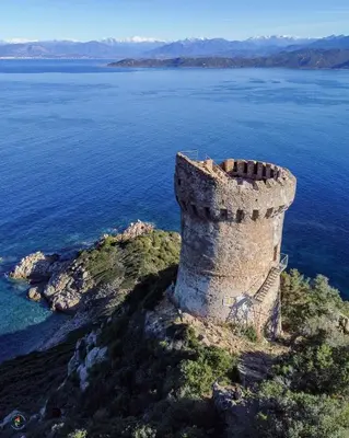 an old tower on the edge of a body of water at Petit coin de paradis, vue panoramique mer &montagne, piscine privée... in Calcatoggio