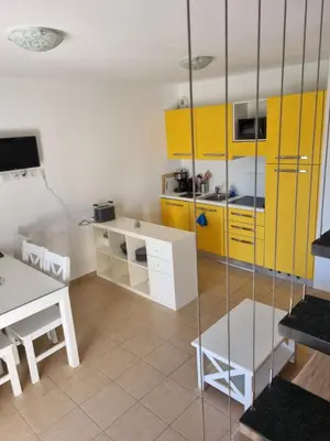 a kitchen with yellow cabinets and a table and a table andasteryasteryasteryastery at Résidence Saint Florent Oletta in Saint-Florent