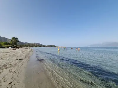 a beach with a group of people in the water at Résidence Saint Florent Oletta in Saint-Florent