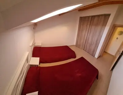 a small room with two beds and a red couch at Résidence Saint Florent Oletta in Saint-Florent