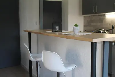 a kitchen with a counter with two white chairs at Location Ajaccio in Ajaccio
