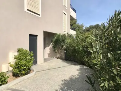 a white building with a walkway next to some plants at 2 pièces vue mer à 3 min des plages in Propriano