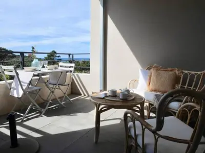a living room with a table and chairs and a balcony at 2 pièces vue mer à 3 min des plages in Propriano