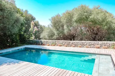 a swimming pool in a yard with a wooden deck at Villa Casta Joia Di Cirendinu in Sainte-Lucie de Porto-Vecchio