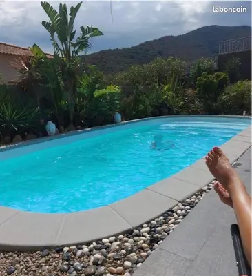 a person sitting next to a swimming pool at Maison T1 bis Corse in Lucciana
