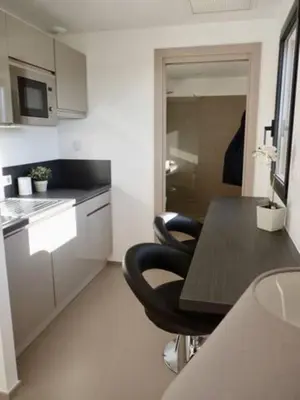 a kitchen with a table and two black chairs at Studio 33m² vue mer in Propriano