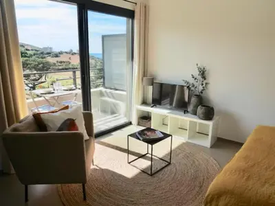 a living room with a chair and a large window at Studio 33m² vue mer in Propriano