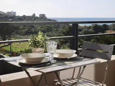 a table with two bowls and glasses on a balcony at Studio 33m² vue mer in Propriano