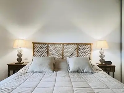 a bedroom with a bed with two tables and two lamps at BEL'ORIZONTE C, 100m des plages et vue mer in Propriano
