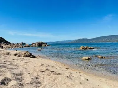 a sandy beach with rocks in the water at BEL'ORIZONTE C, 100m des plages et vue mer in Propriano