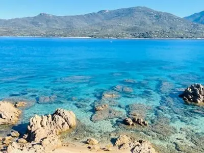a large body of blue water with rocks and mountains at BEL'ORIZONTE C, 100m des plages et vue mer in Propriano