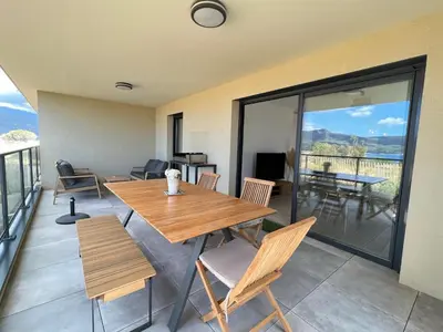 a dining room with a table and chairs on a balcony at BEL'ORIZONTE C, 100m des plages et vue mer in Propriano