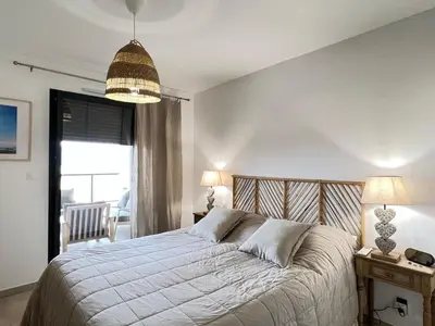 a bedroom with a bed and a table and a window at BEL'ORIZONTE C, 100m des plages et vue mer in Propriano