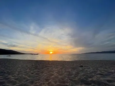 a sunset on a beach with the sun setting at BEL'ORIZONTE C, 100m des plages et vue mer in Propriano