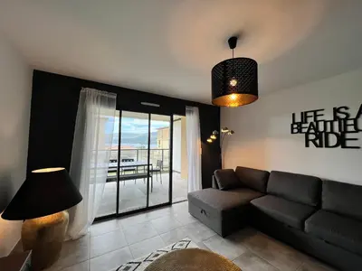 a living room with a couch and a balcony at BEL'ORIZONTE B , proche centre ville et plage in Propriano
