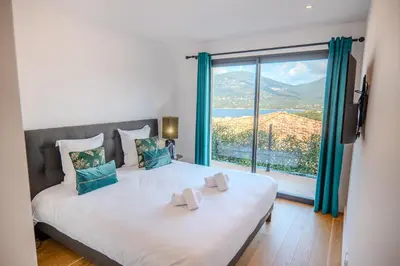 a bedroom with a large bed with a large window at Villa Terra Bella hauteur de la ville avec piscine et vue mer in Propriano