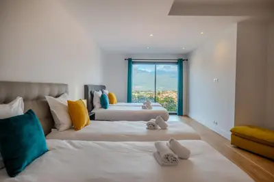 two beds in a room with a large window at Villa Terra Bella hauteur de la ville avec piscine et vue mer in Propriano