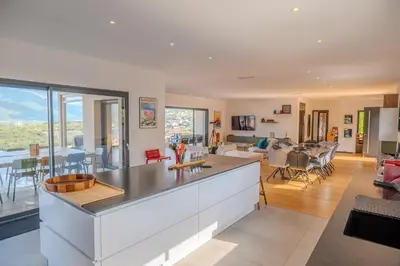 a kitchen and living room with a view of a living room at Villa Terra Bella hauteur de la ville avec piscine et vue mer in Propriano