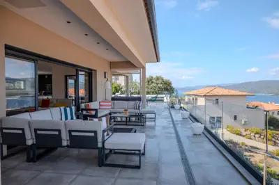 a balcony with white furniture and a view of the water at Villa Terra Bella hauteur de la ville avec piscine et vue mer in Propriano