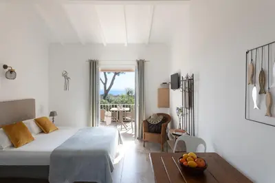 a white bedroom with a bed and a table with a bowl of fruit at Costa Marina in Porto-Vecchio